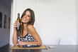 © ADDICTIVE STOCK - Cheerful young woman with drink and food in living room