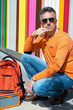© Khorzhevska - Street fashion. Male outdoor portrait. Man sitting near colored