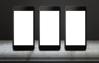 Poster - Three white mobile phones on table with blank, white, isolated display screen for mockup. Mobile app or responsive web site presentation. Vertical position. White table and dark, black background.
