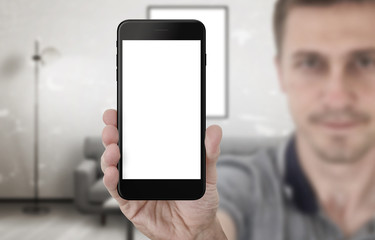 Poster - Guy show black smart phone with isolated screen for app presentation. Mobile mockup. Living room interior in background.