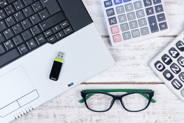 top view of laptop, calculator, glasses and usb flash drive on t