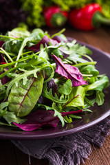 Wall Mural - Fresh salad with mixed greens (arugula, mesclun, mache) on dark wooden background close up. Healthy food.