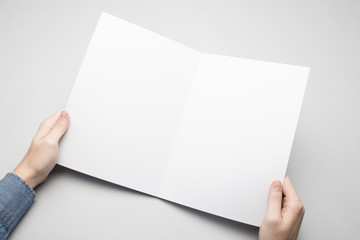 Man in blue shirt is holding a white Bi-Fold paper poster