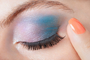 blue eye smokey make up with finger with orange nail polish