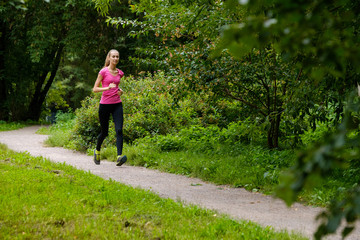 Wall Mural - Young slim woman jogging in a park