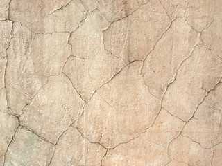 Texture beige cement wall with cracks closeup