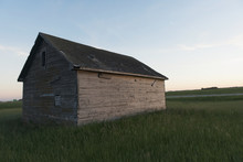 A Wooden Shed In The Middle Of A Grass Field
