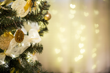 Christmas background. Christmas tree beautifully decorated with balls, bow, lights and dry oranges. Blur background with hearts.