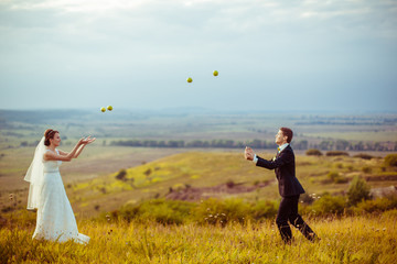 Wall Mural - Wedding couple plays with apples on an empty field