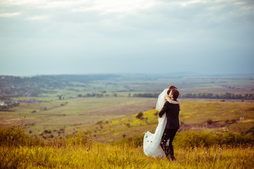 Wall Mural - Groom raises a beautiful bride up in the air while standing on t