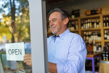 Wall Mural - Wine shop owner holding open sign
