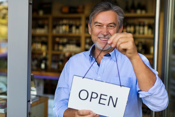 Wall Mural - Wine shop owner holding open sign
