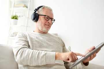 Canvas Print - senior man with tablet pc and headphones at home