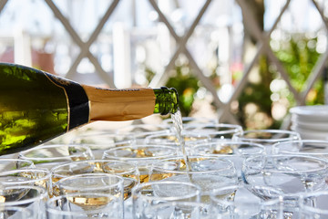 Pouring champagne in flutes standing on table