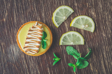 lemon tart desert with cream decoration and mint leaves on wooden table background