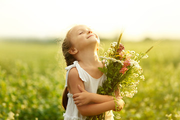 happy little girl with flowers in the field