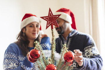 happy family with a young child decorating a christmas tree at h