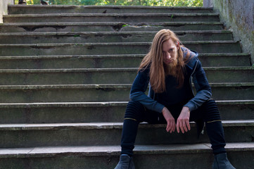 Portrait of man with a long beard and a long hair on the stairca