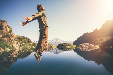 happy man flying levitation jumping with lake and mountains on background lifestyle travel emotions 