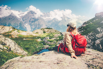 woman traveler with backpack relaxing on cliff with mountains landscape on background travel lifesty