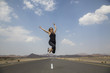 © katiekk2 - woman jumping at a emty road in rural Oman