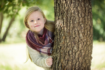 Wall Mural - Unimaginably beautiful blond girl playing in the park hiding beh