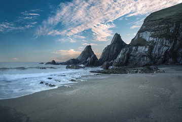 Wall Mural - Stunning colorful sunset over beach landscape with jagged rock f