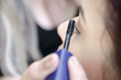 © Domforstock - Woman applied eyeliner by makeup artist, outside the garden. Makeup artist apply eyeliner on the clients eyes