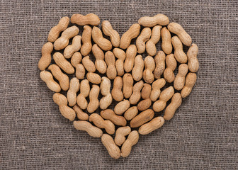 Canvas Print - Pile of peanuts in heart shape on rustic jute cloth. Healthy food concept. Top view.