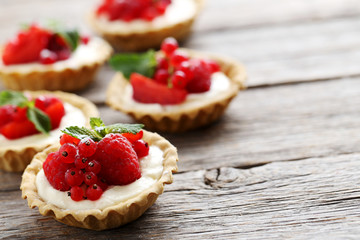 Dessert tartlets with berries on grey wooden background