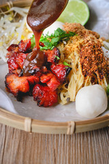 Wall Mural - Egg Noodles and Red Pork with Suace Topping on wood background,