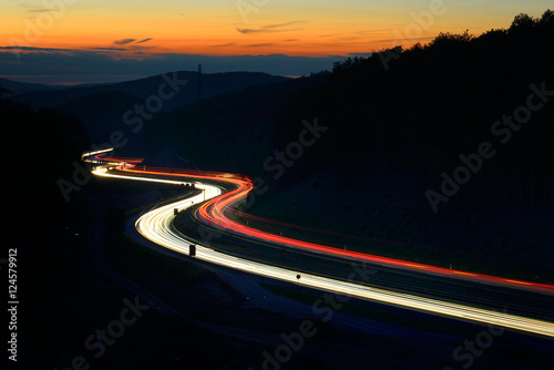 Winding Motorway through Hill Landscape at night, long exposure of headlights an Poster Mural XXL