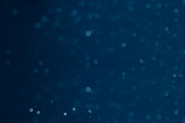 Bokeh dark blue background with blurred rainbow lights. Festive background.