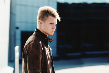 Young handsome stylish man in brown jacket in autumn time outdoor in casual style