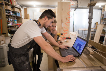 two carpenters work at notebook