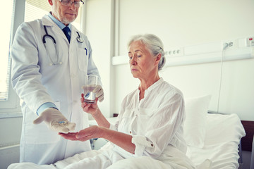 doctor giving medicine to senior woman at hospital