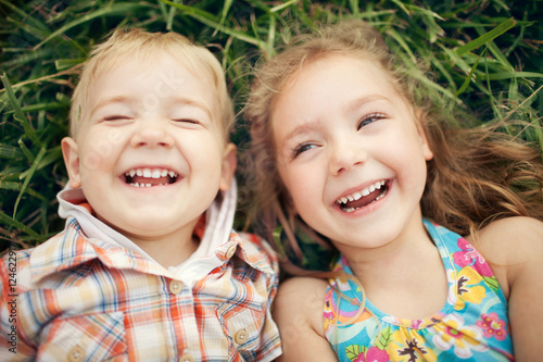 Fotografía Above view portrait of two happy smiling kids lying on green grass