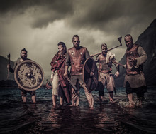A Group Of Armed Vikings Standing On River Shore