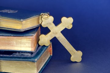 Wall Mural - Religious items: old golden cross and ancient books (Holy Bibles) against blue background