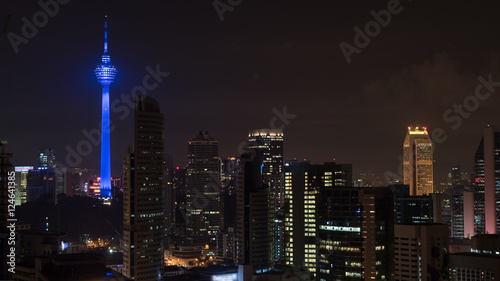Plakat Kuala Lumpur nocą, Malezja. Oświetlone miasto ze świecącą na niebiesko Menara KL Tower