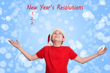 Boy In Santa Hat Looking Upwards On Holiday Christmas Background