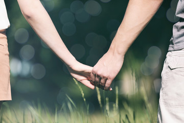 Poster - Young couple holding hands together on blurred nature background