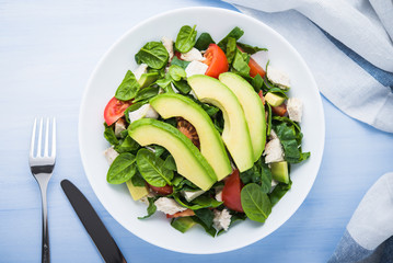 Wall Mural - Fresh salad with chicken, tomatoes, spinach and avocado on blue wooden background top view. Healthy food.