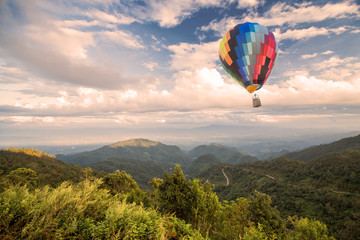 Wall Mural - Hot air balloon over forest mountain and blue sky