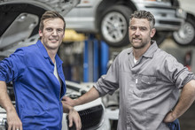 Two Confident Car Mechanics In Repair Garage