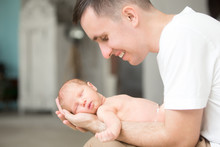 Young Smiling Man Holding Gently A Newborn In His Palms. Family, Healthy Birth Concept Photo
