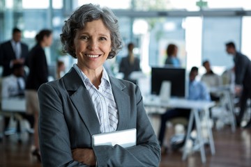 Smiling businesswoman standing with arms crossed in office