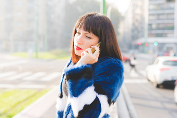 Wall Mural - Half length of young beautiful eastern woman walking outdoor in city back light, talking smart phone, overlooking - technology, communication, work concept