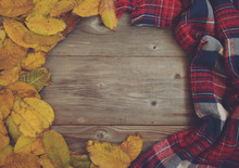 Flat Lay View Of Autumn Leaves And Tartan Textured Scarf On Wood