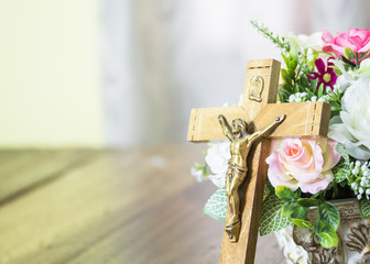 The crucifix of jesus over flower on wooden table background